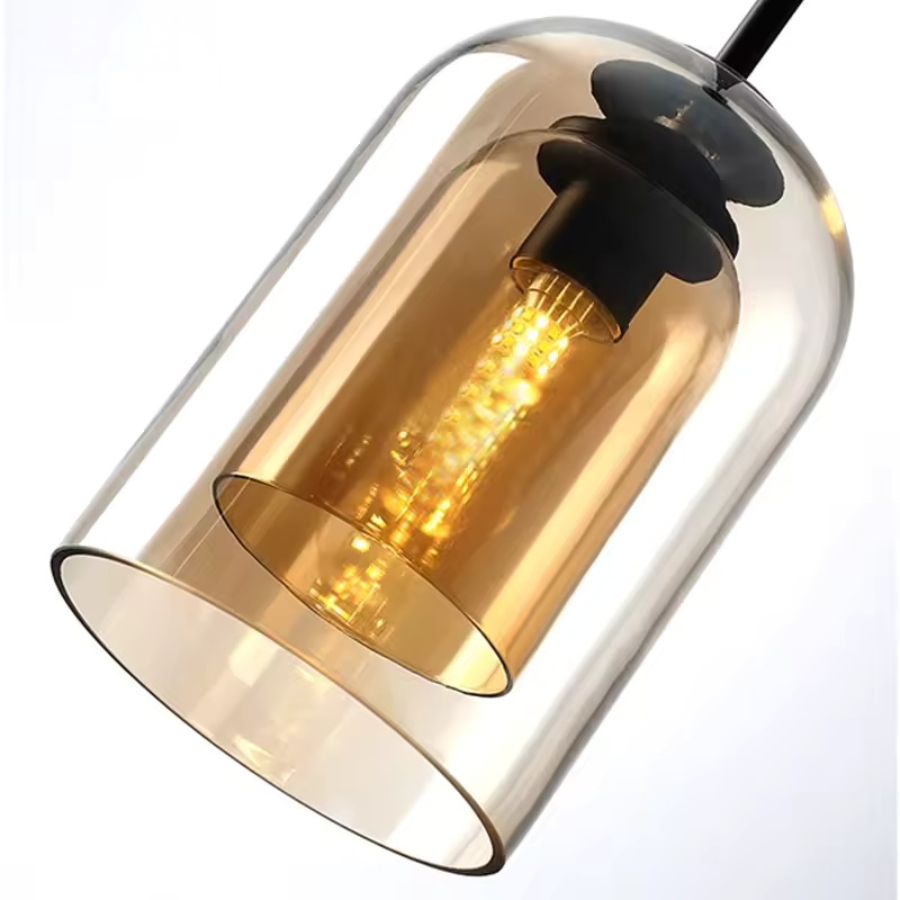 Gros plan sur une suspension en verre ambré à double paroi, avec ampoule filament apparente et allure rétro contemporaine.