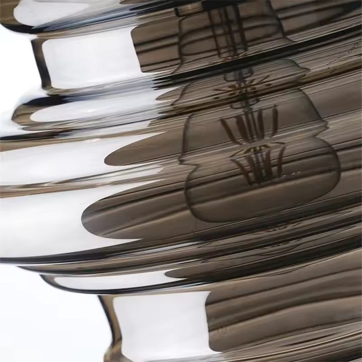 Gros plan sur les reliefs ondulés d'une suspension en verre fumé, aux courbes superposées et reflets élégants.