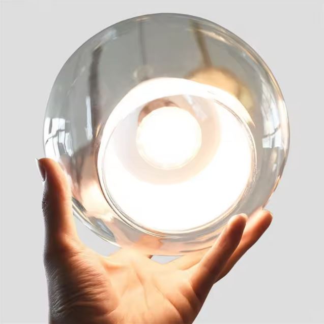 Détail de suspension en verre transparent, globe lumineux au style épuré et contemporain.