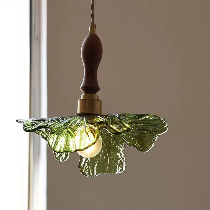 Jeu de lumière à travers le verre vert sculpté, souligné par le bois de noyer et une esthétique botanique raffinée