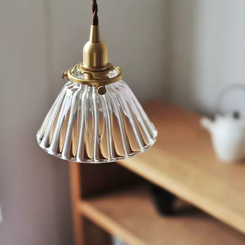 Gros plan sur une suspension en verre cannelé et laiton doré, au style vintage élégant et raffiné