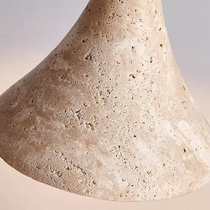 Gros plan sur la texture minérale de la suspension, révélant une pierre claire poreuse au rendu organique et naturel