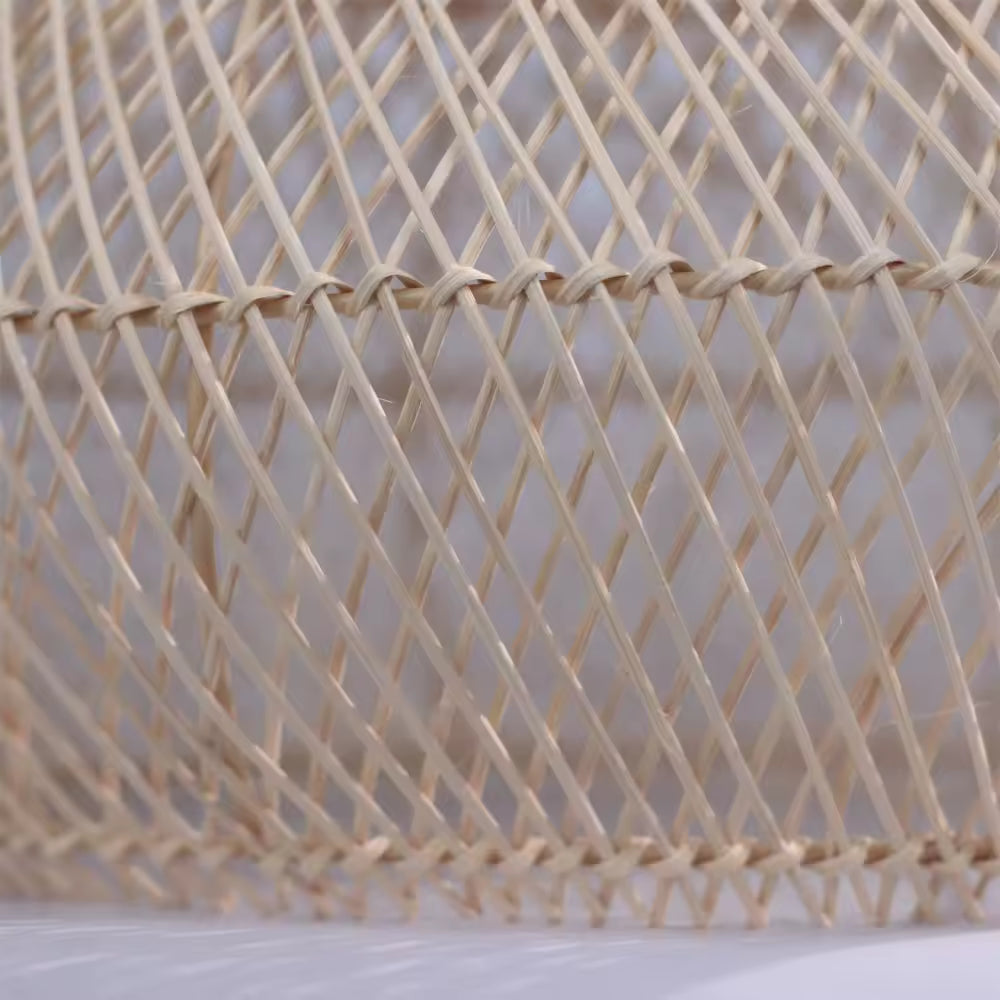 Tressage ajouré en rotin naturel travaillé à la main, soulignant le style artisanal, bohème et organique du luminaire