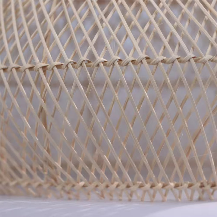 Tressage ajouré en rotin naturel travaillé à la main, soulignant le style artisanal, bohème et organique du luminaire