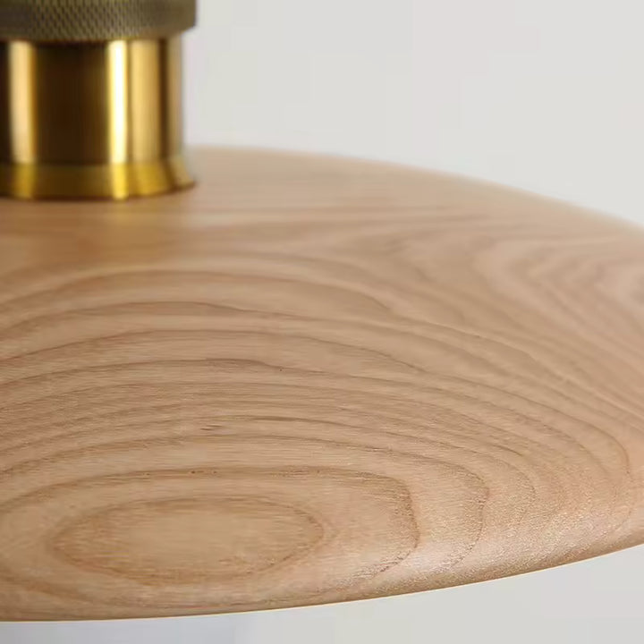 Texture douce et veinage du bois clair mettent en valeur une suspension disque au style japandi, naturel et épuré