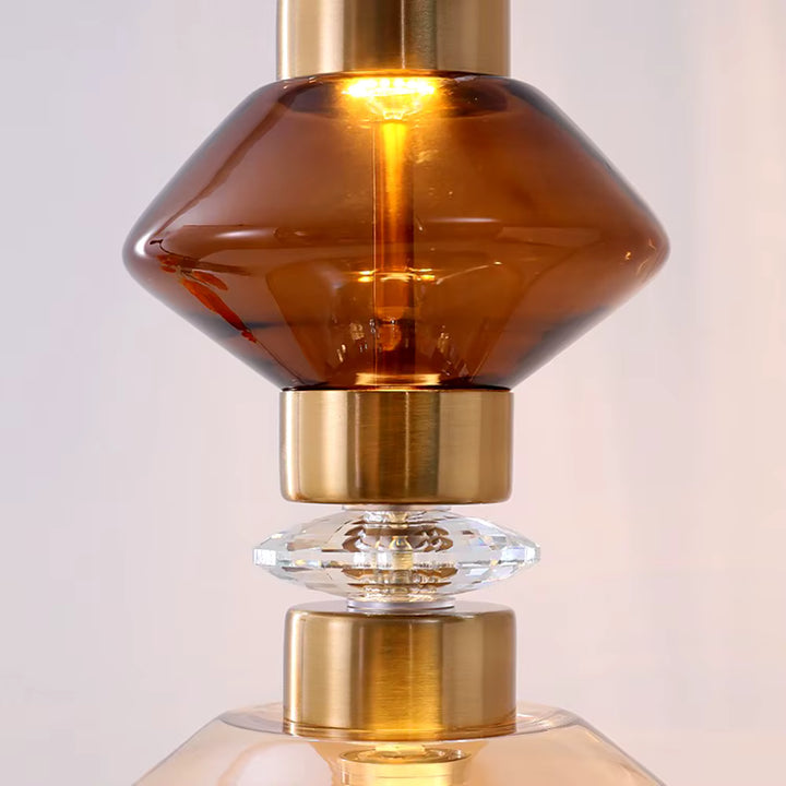 Détail d’un volume en verre brun fumé associé à des bagues dorées et à un élément transparent facetté