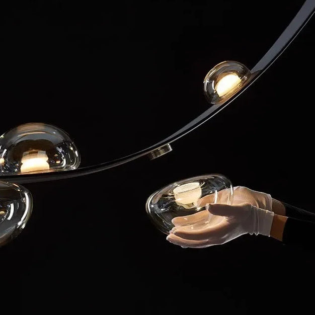 Détail précis de l'accroche en cuir et des globes en verre transparent composant cette suspension.