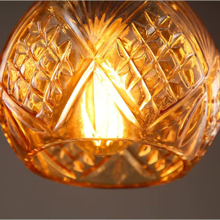 Détail du verre taillé ambré d’une suspension flacon, révélant ses motifs géométriques et son esprit rétro raffiné