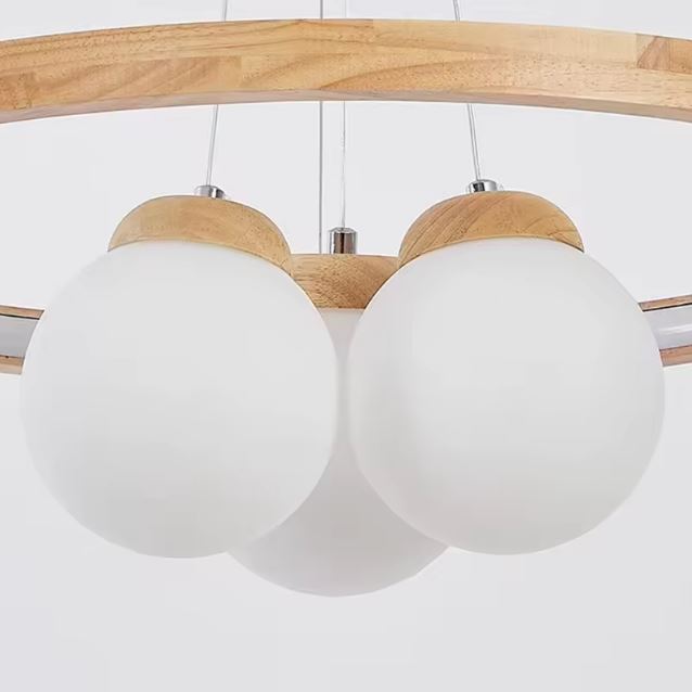 Détail des globes en verre blanc opalin et finitions bois naturel d’une suspension élégante au style scandinave et épuré.