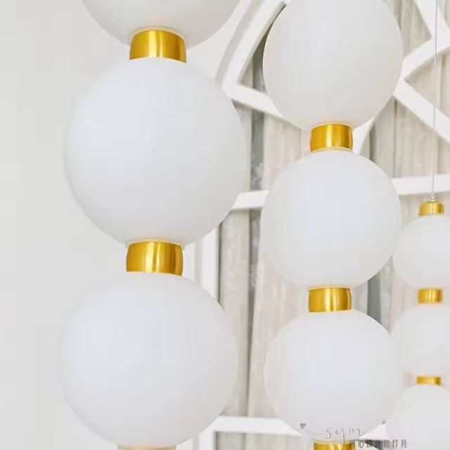 Gros plan sur une suspension perle avec détails dorés, apportant une touche contemporaine et lumineuse à la décoration.