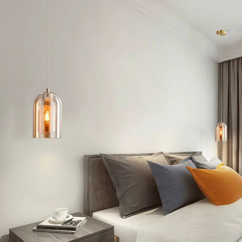 De chaque côté du lit, des suspensions en verre ambré diffusent une lumière douce dans une chambre moderne et élégante.