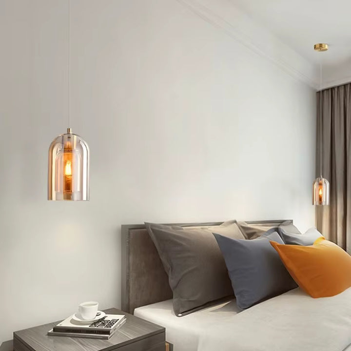 De chaque côté du lit, des suspensions en verre ambré diffusent une lumière douce dans une chambre moderne et élégante.