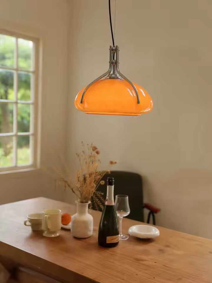 Dôme orange brillant à armature chromée au-dessus d’une table, dans un décor vintage aux influences Space Age