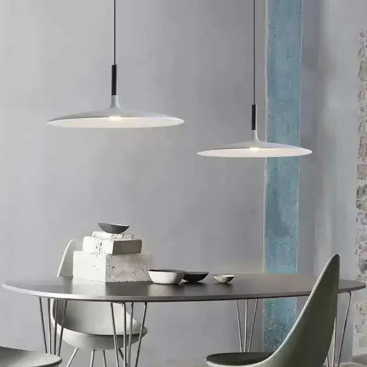 Double suspension UFO en métal blanc installée dans un espace repas minimaliste et lumineux.
