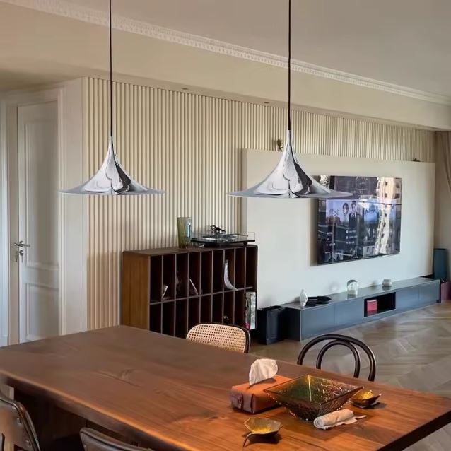 Duo de suspensions chrome au-dessus d’une table en bois, entre élégance vintage, design italien et modernité épurée.