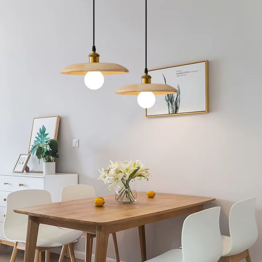 Au-dessus de la table, deux suspensions en bois clair et globe lumineux créent une ambiance japandi douce et épurée