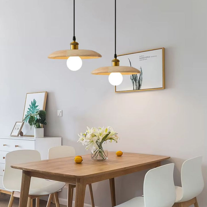 Au-dessus de la table, deux suspensions en bois clair et globe lumineux créent une ambiance japandi douce et épurée