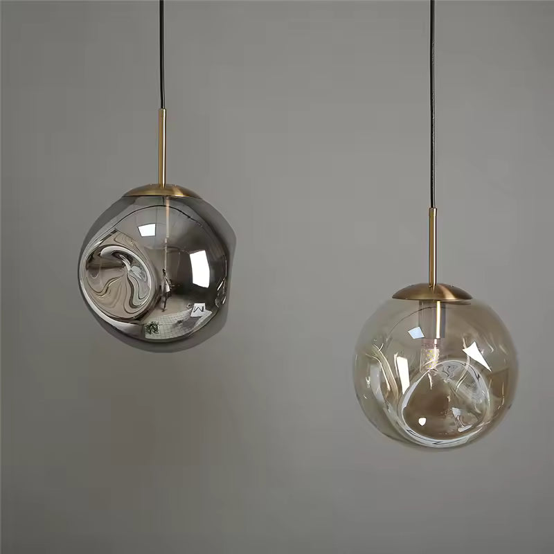 Deux suspensions globe en verre ondulé, fumé et ambré, avec finitions dorées au style sculptural et raffiné