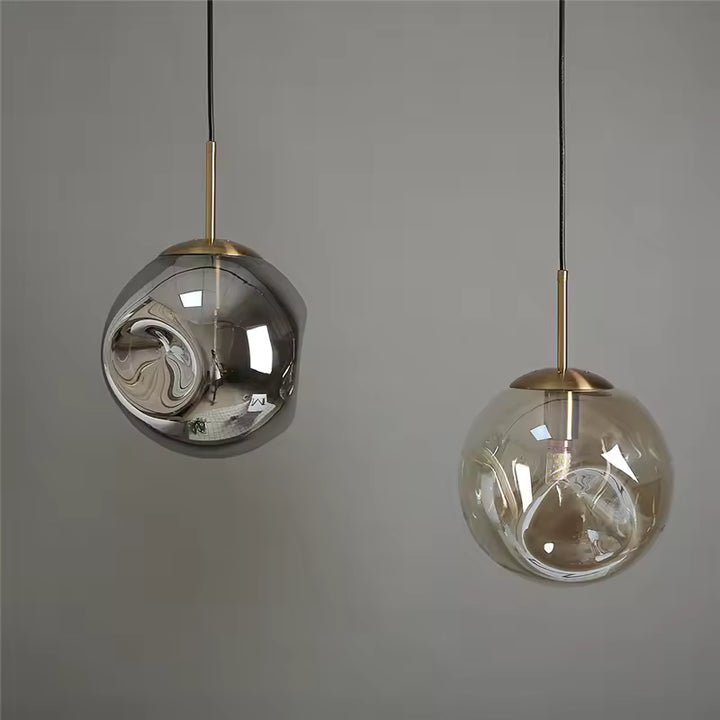 Deux suspensions globe en verre ondulé, fumé et ambré, avec finitions dorées au style sculptural et raffiné