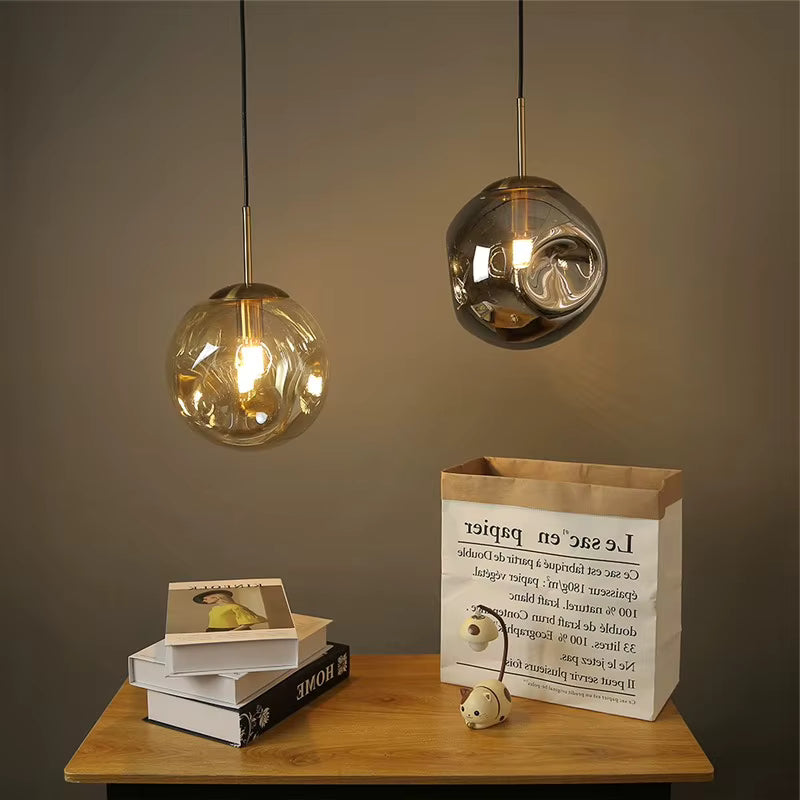 Deux suspensions globe en verre ondulé fumé et ambré, éclairées d’une lumière chaude au style chic et contemporain