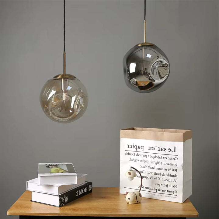 Deux suspensions globe en verre ondulé avec finitions dorées, dans une composition décorative moderne et raffinée