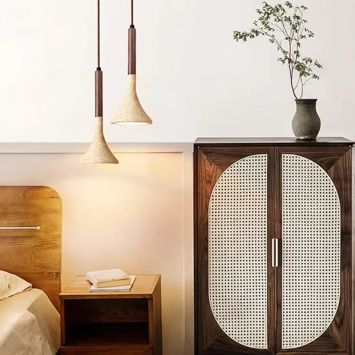 Deux luminaires en pierre claire et bois foncé accompagnent une chambre naturelle avec mobilier en cannage
