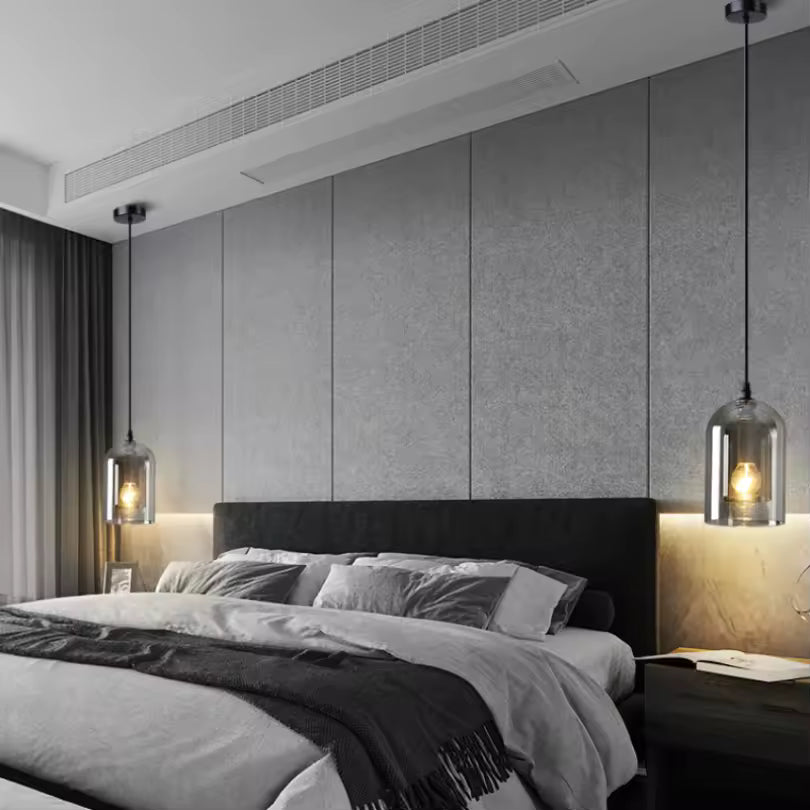 Deux suspensions en verre fumé à ampoules apparentes encadrent un lit double dans une chambre au style contemporain épuré.