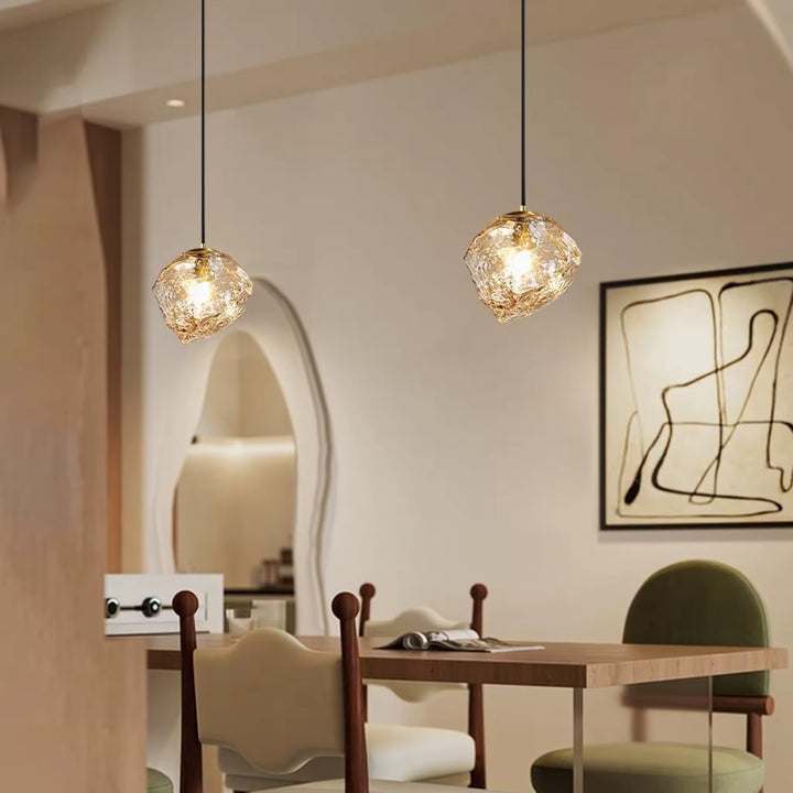 Au-dessus de la table, deux suspensions en verre sculpté diffusent une lumière chaleureuse dans un décor contemporain