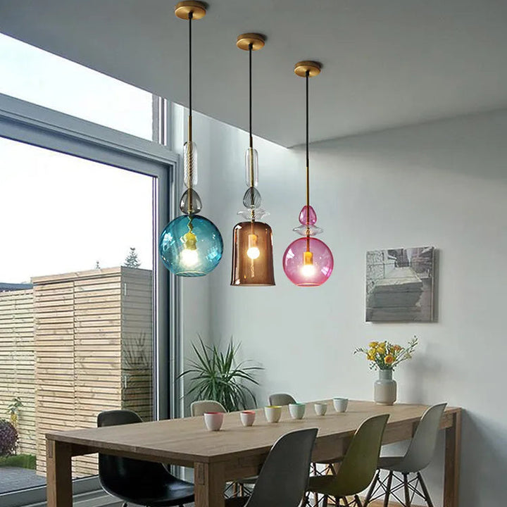 Trio de lampes suspensions en verre soufflé illuminant chaleureusement une table de salle à manger.