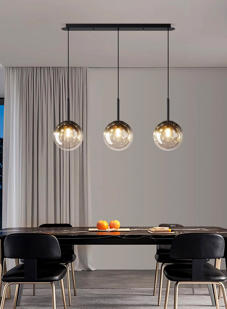 Éclairage design composé de sphères en verre alignées pour illuminer une salle à manger.