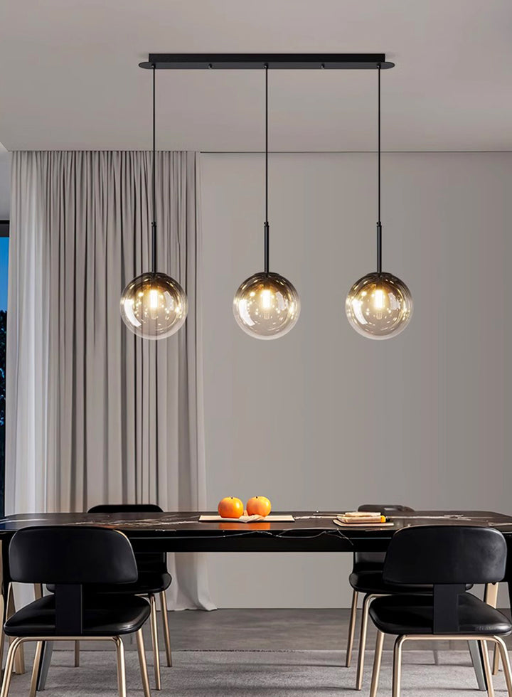 Éclairage design composé de sphères en verre alignées pour illuminer une salle à manger.