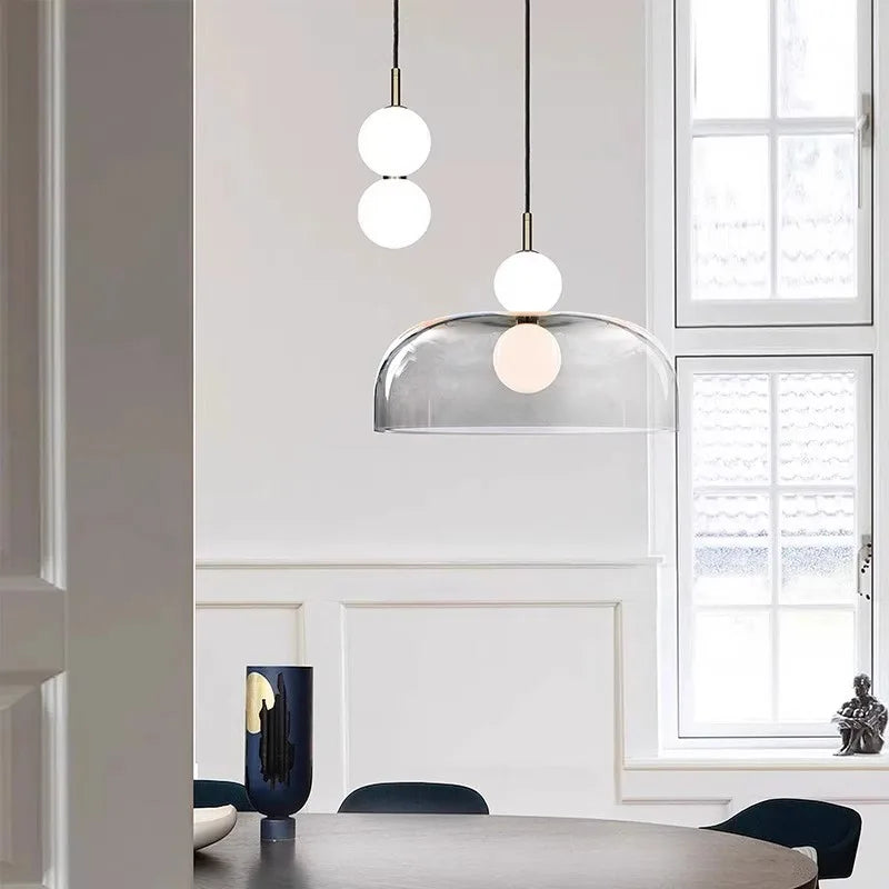 Vue rapprochée d'une suspension haut de gamme en verre éclairant un intérieur épuré et chic.