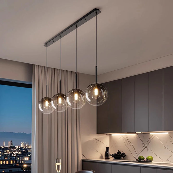 Éclairage suspendu contemporain en barre avec alignement de sphères en verre face à une grande fenêtre.