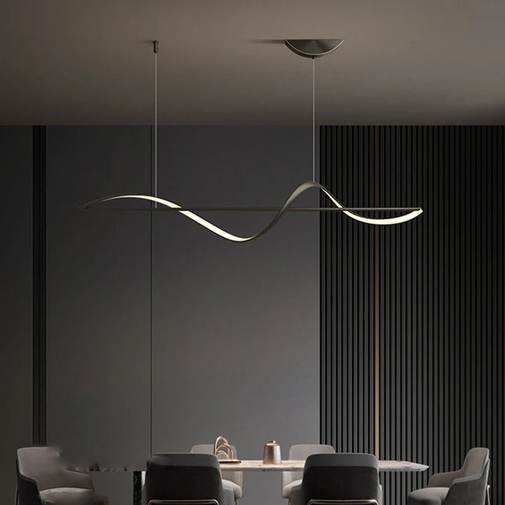 Éclairage suspendu au design minimaliste mettant en valeur un ruban d'or sinueux au-dessus de la table.