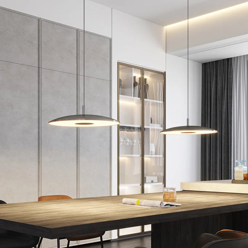 Agencement de luminaires suspendus contemporains valorisant une grande tablée dans un intérieur chic.