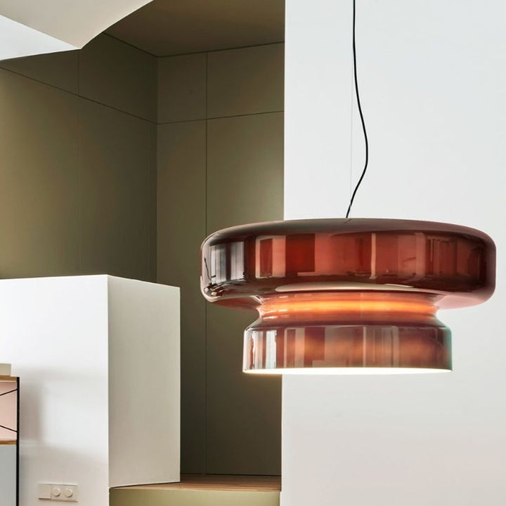 Éclairage suspendu en verre fumé rouge au design contemporain dans une pièce de vie épurée.