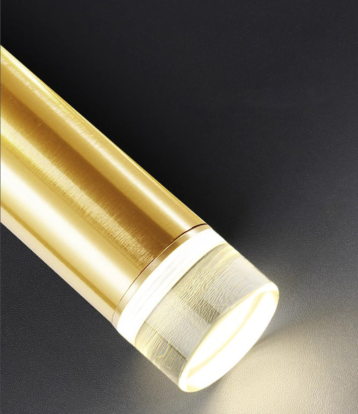 Zoom sur l'embout lumineux à LED d'un tube suspendu doré diffusant une lumière chaleureuse.
