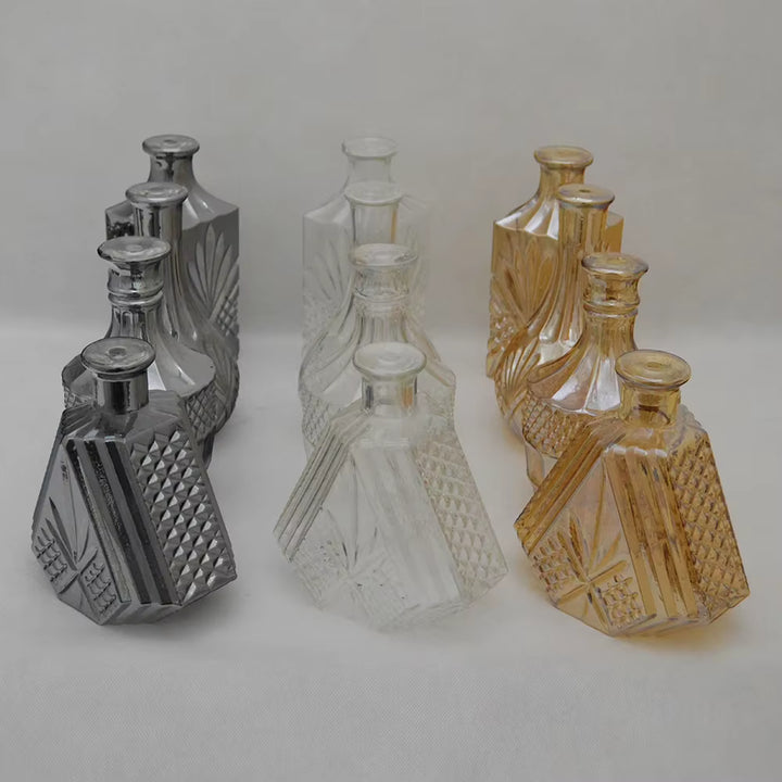 Déclinaisons de flacons en verre taillé fumé, transparent et ambré, aux motifs géométriques d’inspiration vintage