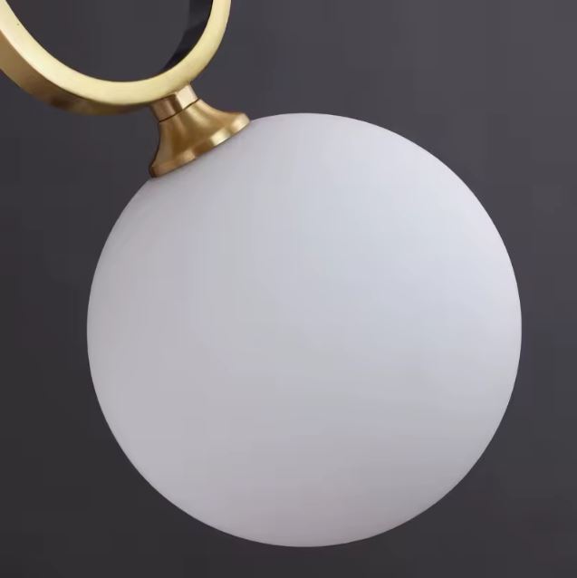 Globe opalin blanc pour suspension en laiton, détail luminaire au style Bauhaus doux et contemporain.