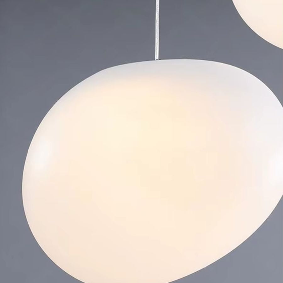 Gros plan sur un globe opalin aux lignes organiques diffusant une lumière douce sur cette suspension moderne