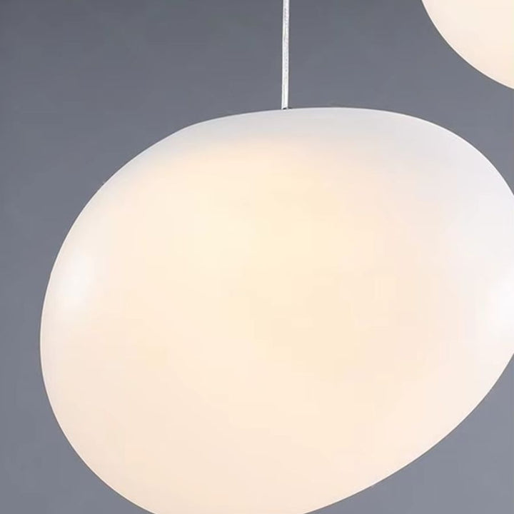 Gros plan sur un globe opalin aux lignes organiques diffusant une lumière douce sur cette suspension moderne