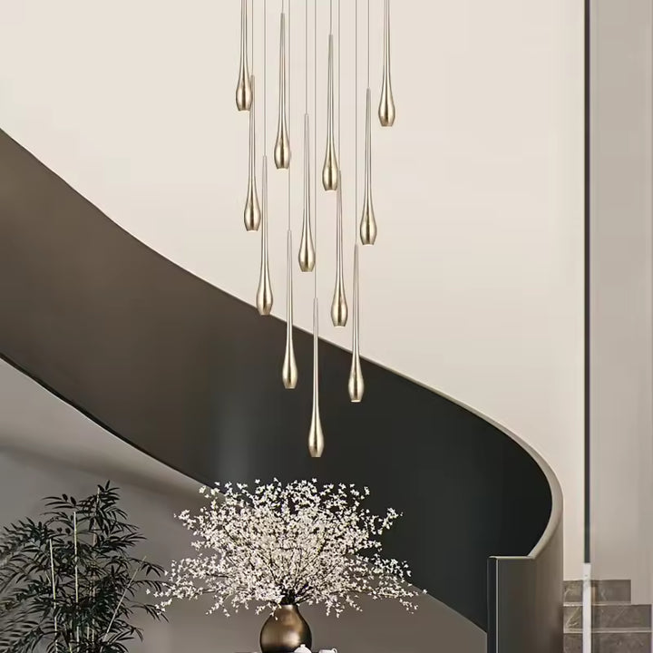 Une pluie de gouttes dorées forme un lustre cascade sculptural, idéal pour sublimer un escalier contemporain