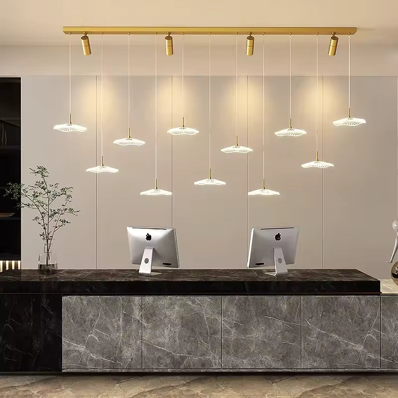 Un lustre doré au style contemporain associe 11 ombrelles LED et quatre spots orientables au-dessus d'un comptoir d'accueil.