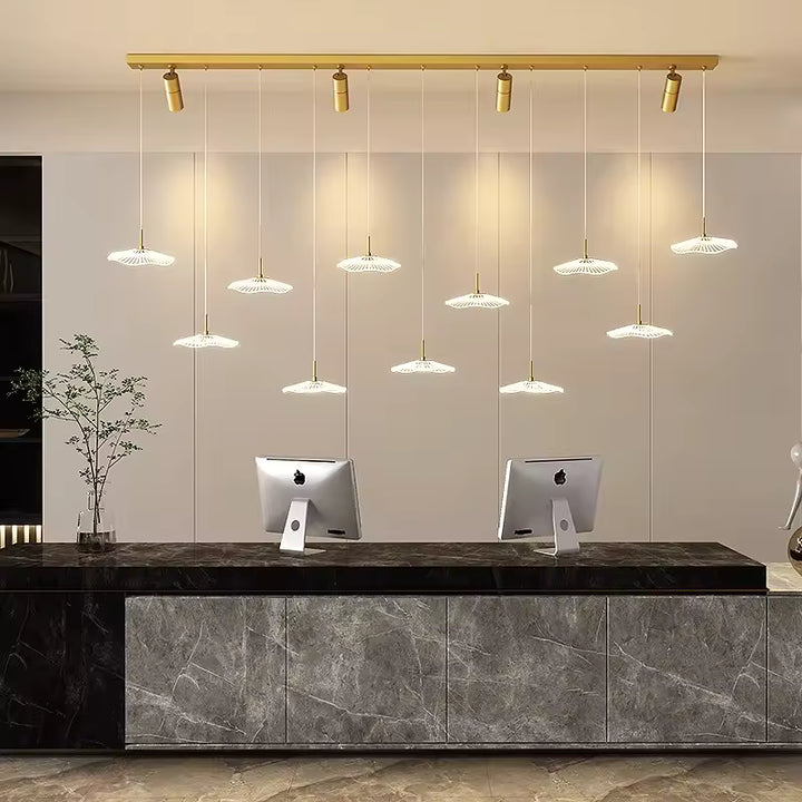 Un lustre doré au style contemporain associe 11 ombrelles LED et quatre spots orientables au-dessus d'un comptoir d'accueil.