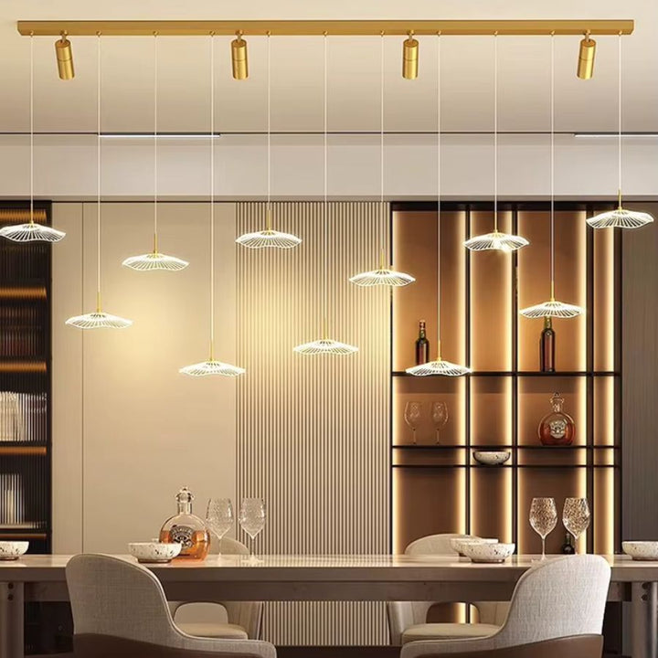 Une suspension dorée au design architectural déploie 11 ombrelles LED en cascade et quatre spots au-dessus d'une grande table.