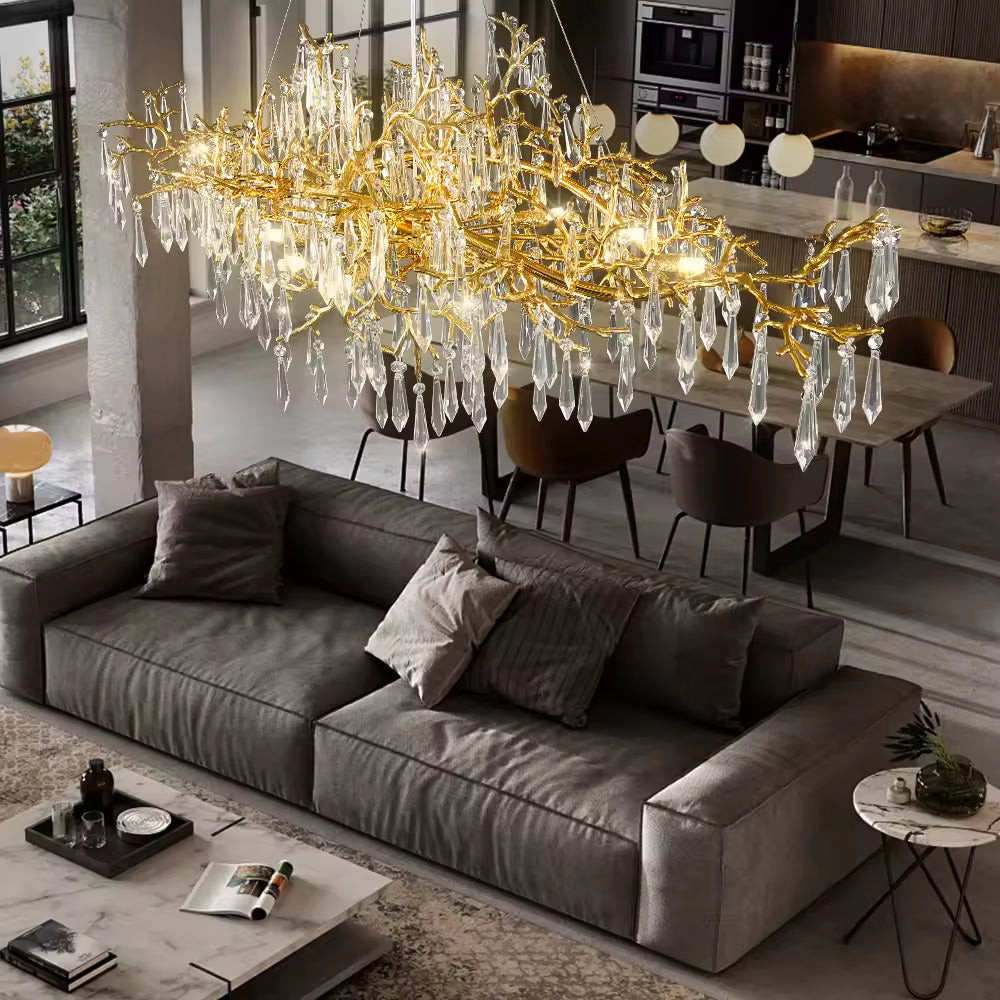 Pièce maîtresse d’un intérieur moderne, ce grand lustre mêle pampilles de cristal et branches dorées au style organique luxueux