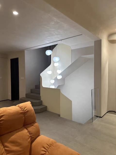 Grande suspension boule suspendue dans un escalier moderne au style épuré et chaleureux.
