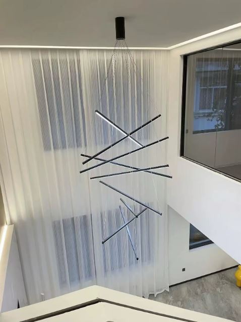 Grande suspension cage d’escalier LED au design minimaliste noir et blanc, idéale pour un intérieur épuré et lumineux.