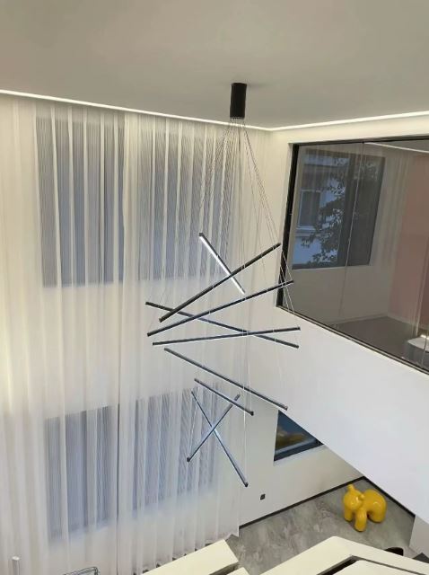 Grande suspension cage d’escalier LED, intégrée dans un intérieur moderne à très grande hauteur sous plafond.