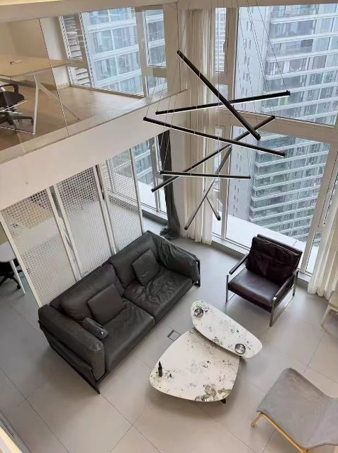 Grande suspension cage d’escalier LED noire, parfaite pour un loft urbain à plafond cathédrale avec verrière.
